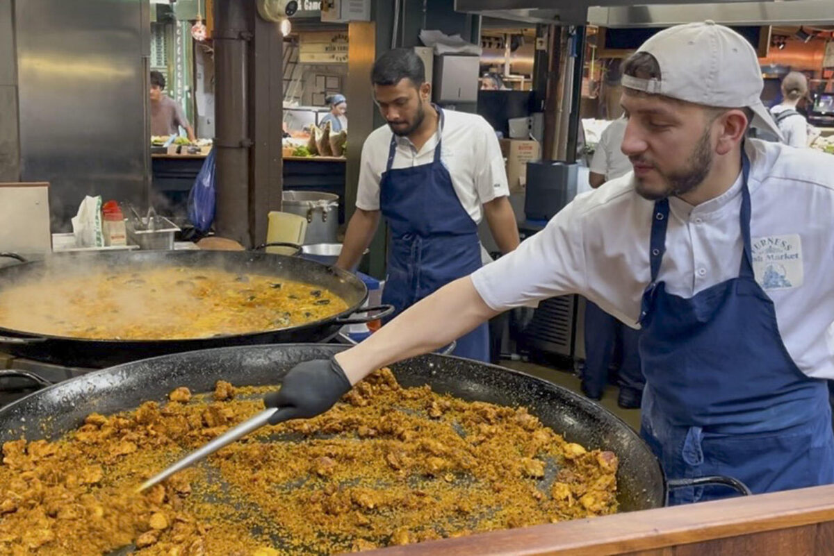 El mercado gastronómico de Borough, uno de los más populares de Londres, recibe a diario largas colas de visitantes para comprar una porción de paella en el puesto de arroces que causa furor entre los turistas y visitantes y donde se venden más de 1.000 raciones a diario. Son las diez de la mañana y huele a aceite de oliva, ajo, cebolla, pimiento y tomate rallado, el tradicional sofrito de paella. También se escucha cómo las cucharas rascan el fondo de la paellera para obtener el característico'socarrat'. Esta escena podría ser la típica imagen, salvando la hora, en cualquier restaurante, bar o calle del Mediterráneo español. Sin embargo, el lugar es el mercado gastronómico de Borough en Londres.-EFE/ Luis Campello