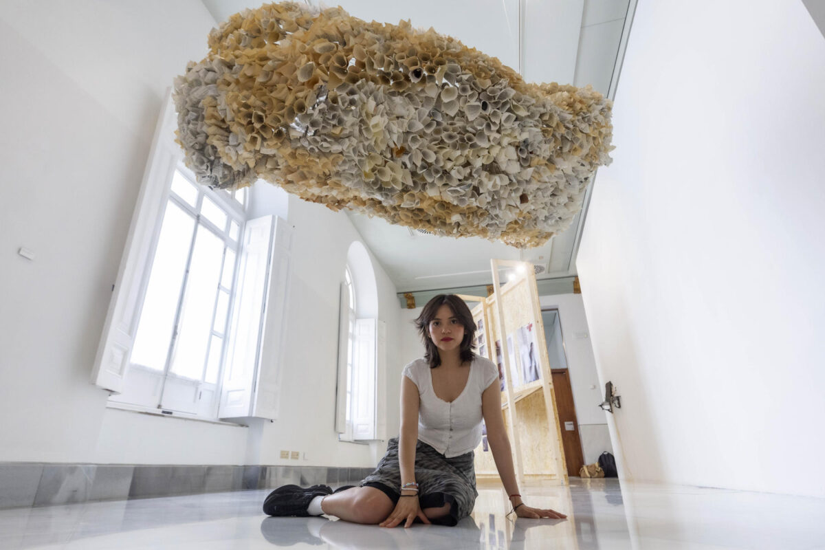 La artista ecuatoriana Nebraska Flores posa junto a su obra'Escritura fósil', en la muestra titulada'Los de aquí', en la que participan nueve artistas de Ecuador que hacen dialogar el arte contemporáneo con los movimientos migratorios, en Cartagena (España), con motivo del Festival Mar de Músicas, este año dedicado a Ecuador. EFE/Marcial Guillén