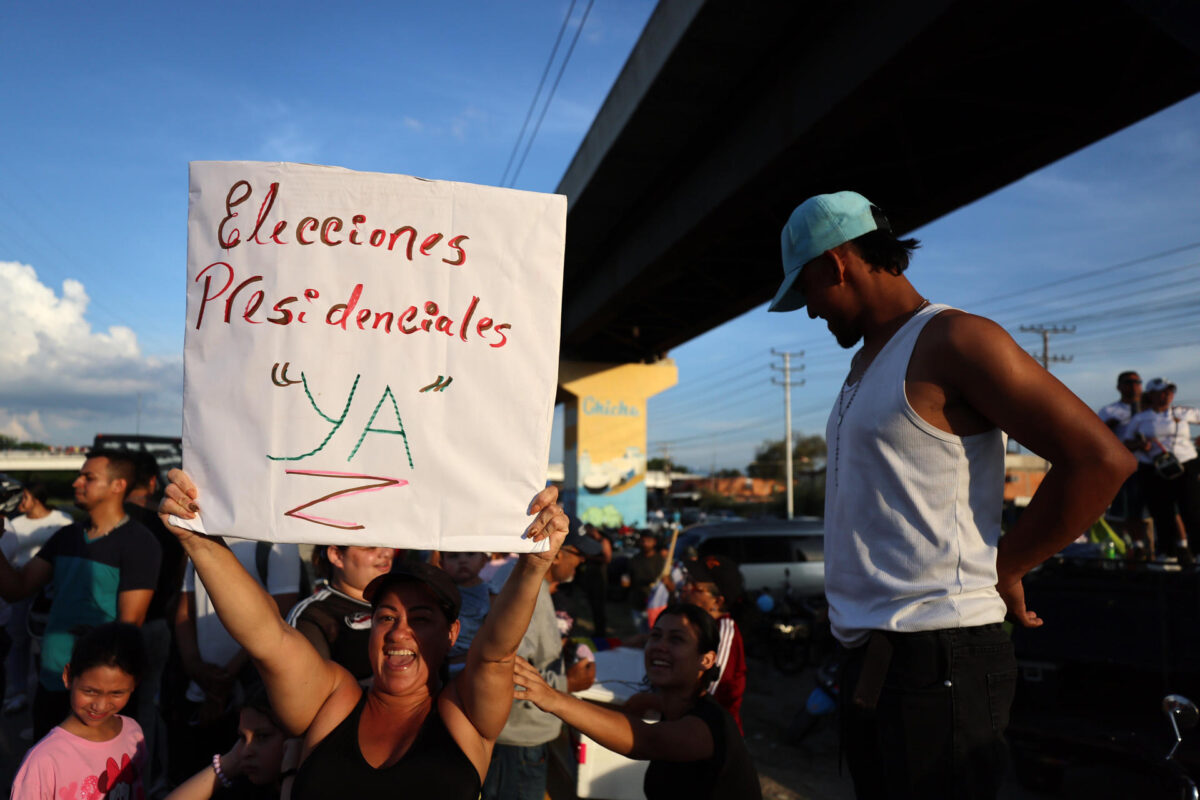 Una mujer sostiene un cartel mientras espere la llegada de la líder opositora y premio nobel de la paz 2025, María Corina Machado, este domingo en Maracay (Venezuela). EFE/ Miguel Gutiérrez