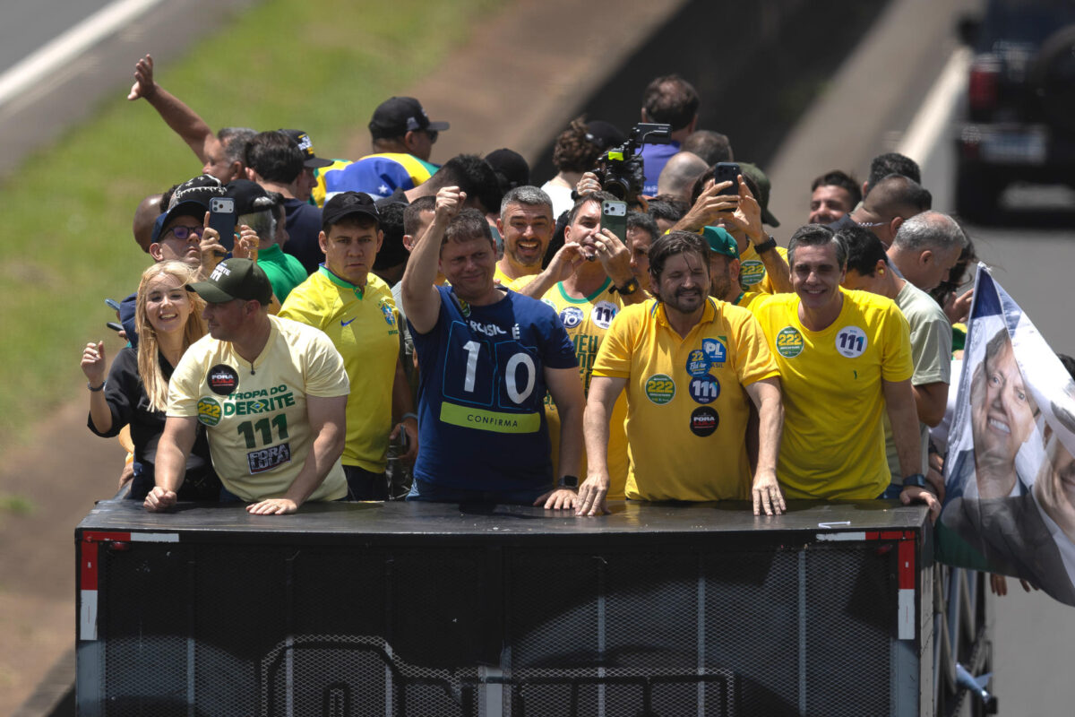 El candidato a la presidencia de Brasil por el Partido Liberal, Flávio Bolsonaro (c-atras), reacciona junto al candidato al Gobierno de Sao Paulo, Tarcísio de Freitas (c), durante una caravana este sábado, en Santa Bárbara d’Oeste (Brasil). EFE/ Isaac Fontana